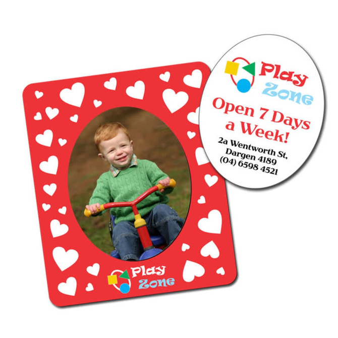A magnetic photo frame in red with heart patterns, featuring an oval cutout for a photo and a circular card with details.