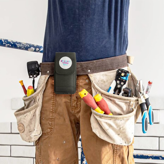 A black phone pouch with a belt clip attached to a tool belt, surrounded by various tools.