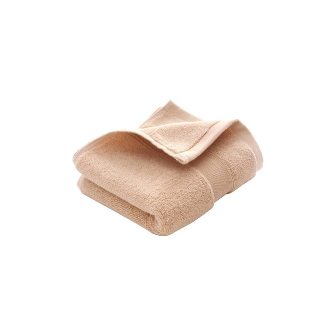 A folded beige cotton hand towel with a textured surface, featuring a logo on the side.