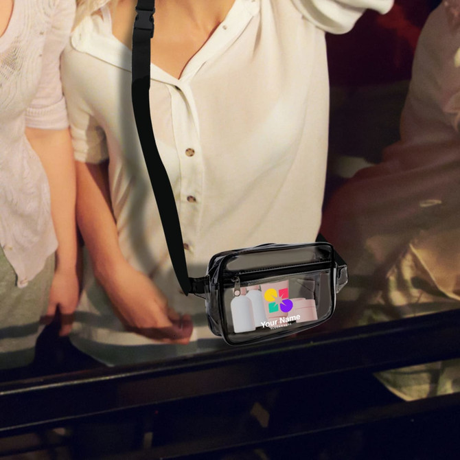 A clear black fanny pack with a strap and branding visible on the front, placed on a surface.