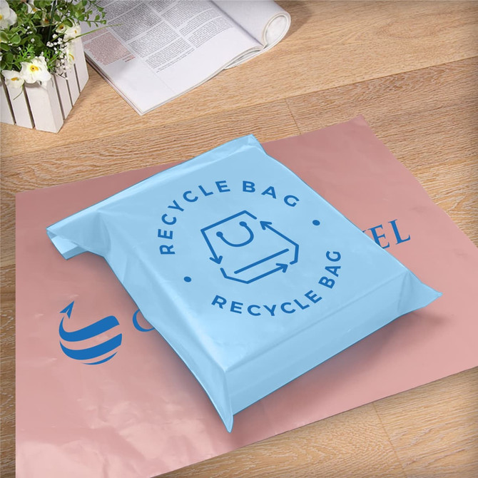 A light blue self-sealing plastic mailing bag on a pink background, featuring a logo.