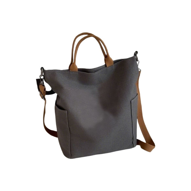 A grey vintage style canvas bag with brown straps and two side pockets, featuring a small logo.