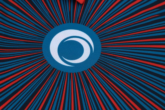 A vibrant blue and red sublimated sport polo featuring a circular logo at the centre. 