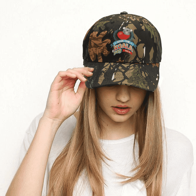 A camouflage cap featuring a mix of browns and greens, with a logo on the front.