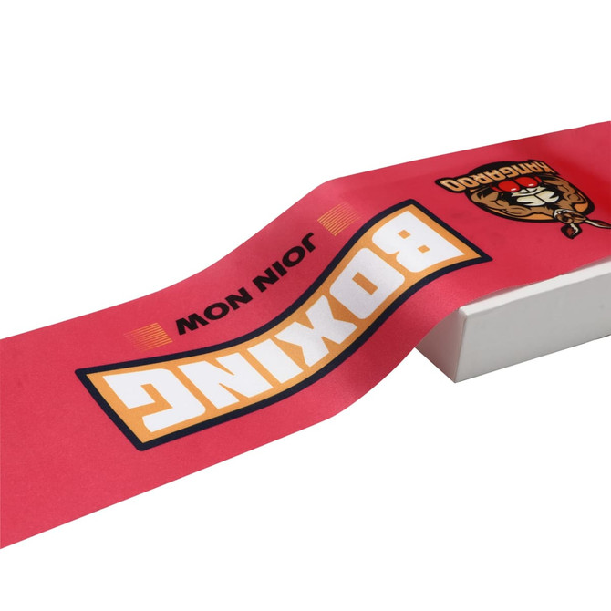 A red ribbon with graphics including the word "Boxing" and a logo, placed on a white surface.