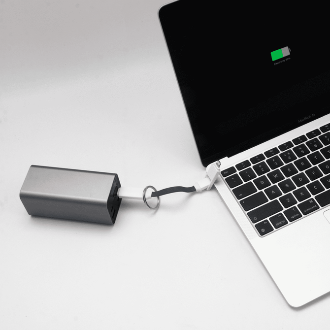 A silver charging cable connected to a laptop, with a visible battery charge indicator on the screen.