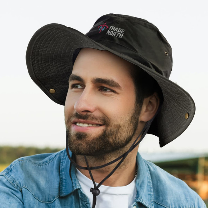 A black oilskin wide brim hat with a logo, featuring a drawstring and a textured brim, worn by a smiling man.