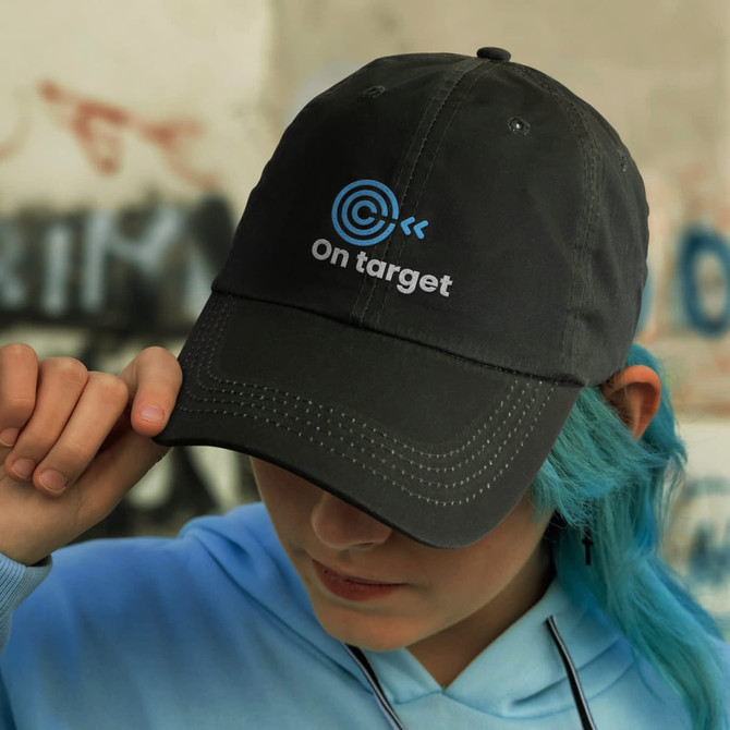 A black cap with an embroidered logo and text, featuring a curved brim and adjustable strap.