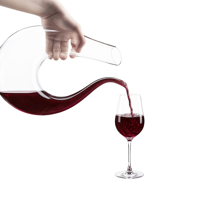 A U-shaped glass wine decanter in clear glass, pouring red wine into a wine glass.