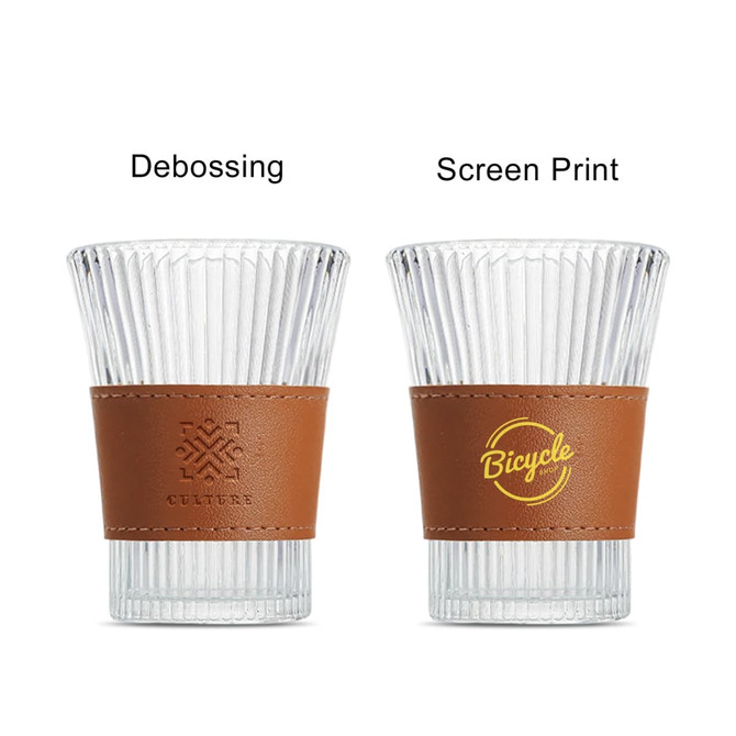 A drink bottle with a clear glass body and a brown leather cup sleeve. It features a logo on one side.