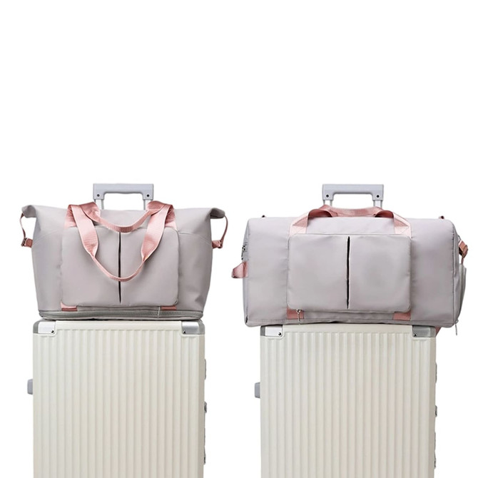 A grey foldable sports duffle bag with pink accents placed on a luggage trolley. The bag features a logo.