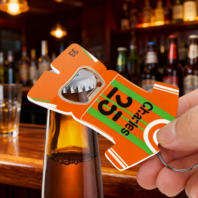 A drink bottle opener keyring shaped like a sport jersey in orange with green stripes and a logo.