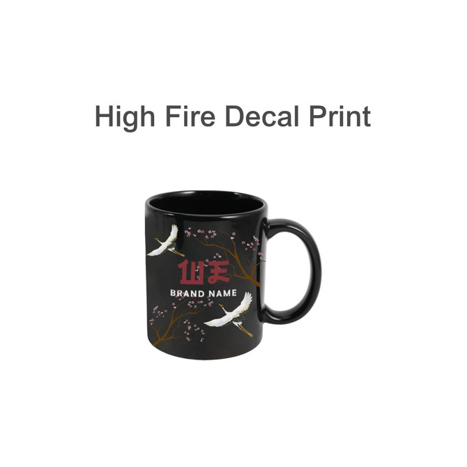 A black mug featuring a decorative design with cranes and floral elements. It has a brand logo.