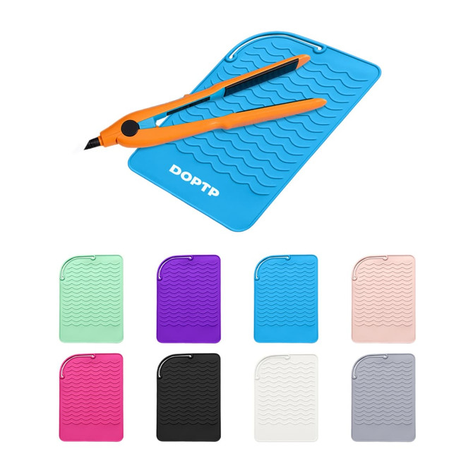 A blue silicone hair straightener pad with wavy texture and a pair of orange scissors, surrounded by various coloured pads.