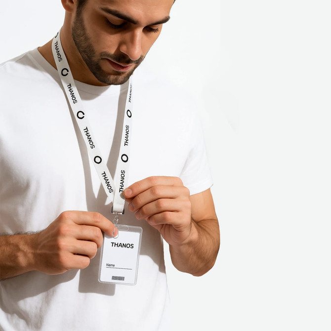 A man wearing a white t-shirt adjusts a lanyard with a name tag. The lanyard is white with a logo.