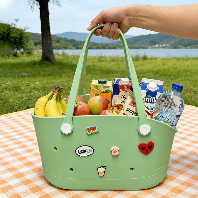 A light green EVA pet bag filled with fruits, drinks, and decorated with playful stickers. It has a logo on one side.