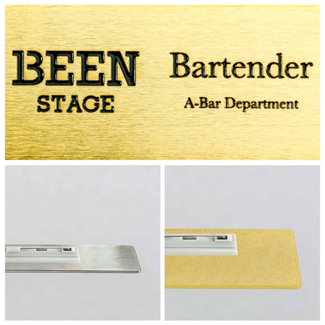 A metal name badge in gold with a brushed finish, featuring a silver backing. Includes a logo.