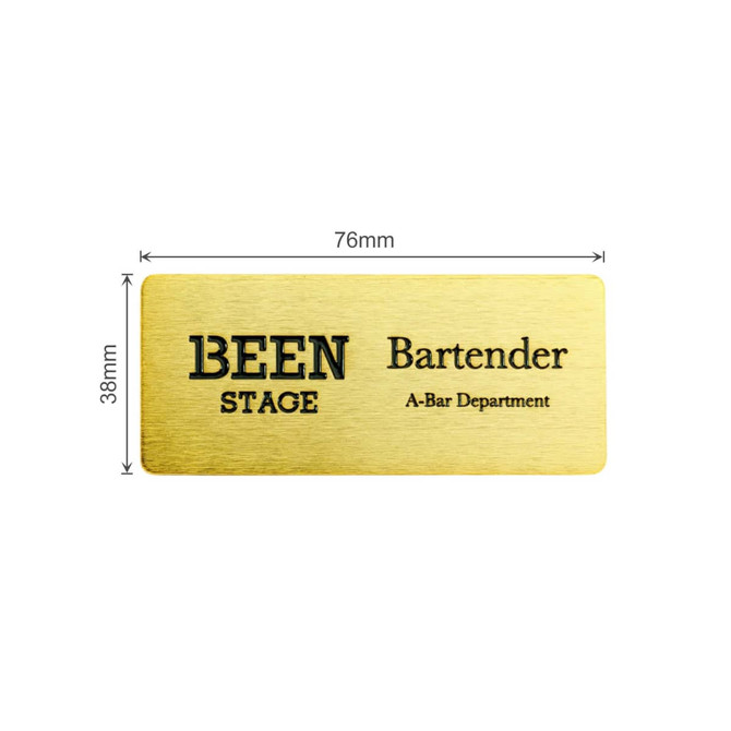 A metal name badge in gold, featuring engraved text and a logo, measuring 76mm by 38mm.