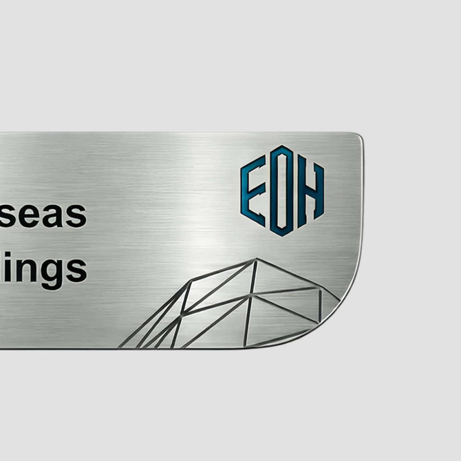 A custom metal name badge featuring a brushed silver finish and a logo in blue and black.