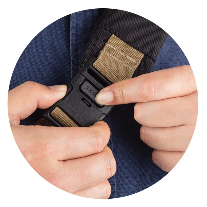 A hand adjusting a buckle on a strap, showcasing a dark fabric and a tan webbing. The image has a circular frame.