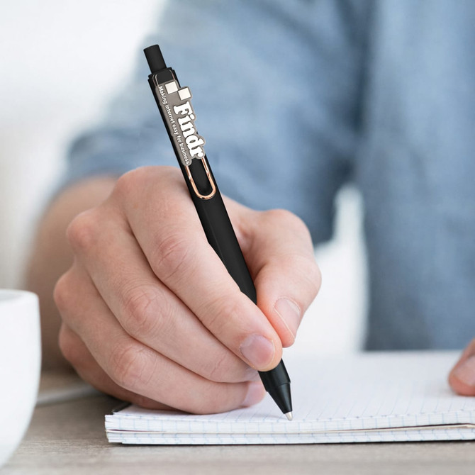 A black PVC pen held by a person writing on a notepad, featuring a logo on its side.