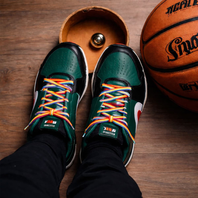 Colourful custom shoe laces in a pair of black and green sneakers, with a basketball and wooden box in the background.