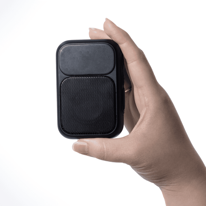 A compact black speaker held in one hand, featuring a textured front and smooth back, with a logo present.