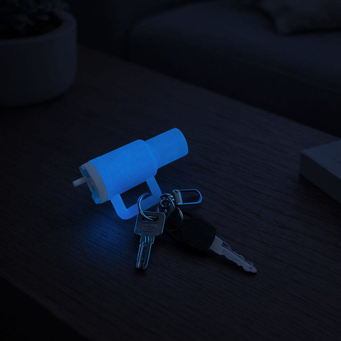A glow-in-the-dark mini tumbler keyring in blue displaying a keyring and keys on a wooden surface.