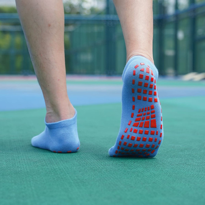 Low cut gripper socks in light blue with red grip pattern on the soles, displayed on a person's feet.