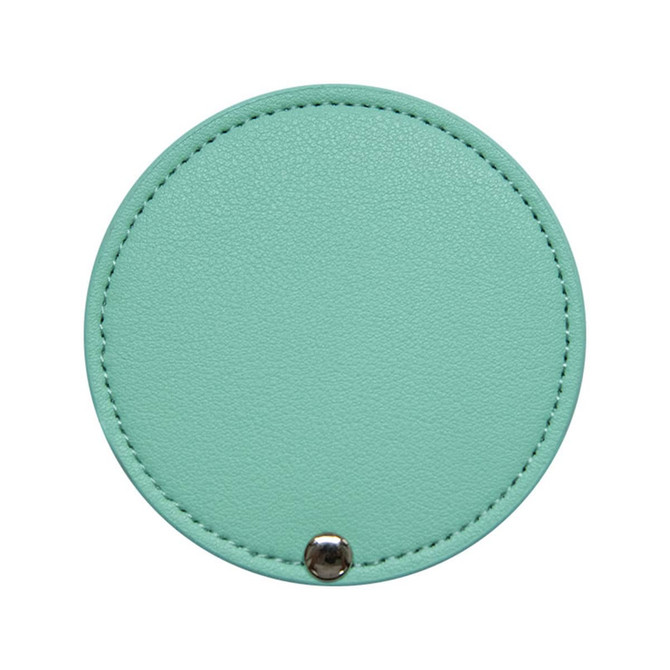 A round makeup mirror in mint green with a textured surface and a silver snap button.