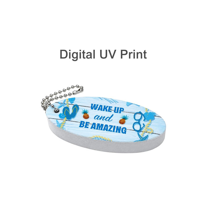 A blue oval keychain featuring a digital print design with sunglasses, pineapples, and a motivational phrase. It has a chain attachment.