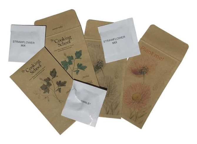 A collection of seed envelopes in various designs and earthy tones, featuring floral and vegetable illustrations.