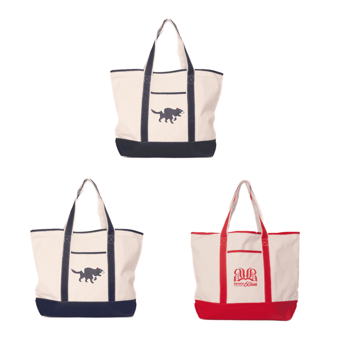 A canvas tote bag featuring a dinosaur design, available in cream, navy, and red variations. It has a logo as well.