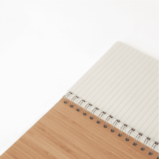 A bamboo notebook with a spiral binding, featuring a textured bamboo cover and lined pages inside.