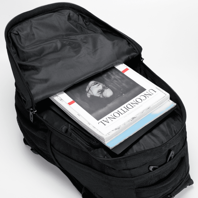 A black backpack with a partially open zipper, revealing magazines and documents inside. It features a logo on the exterior.
