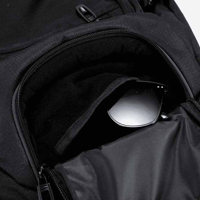 A black backpack with a zippered pocket containing a pair of sunglasses, featuring a sleek design and branding.