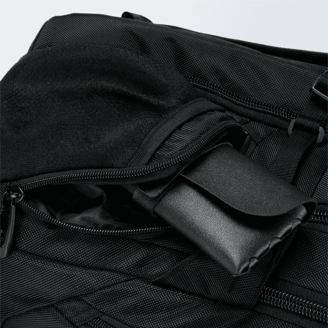 A black backpack featuring multiple zippered compartments, with one compartment containing a rolled-up item.