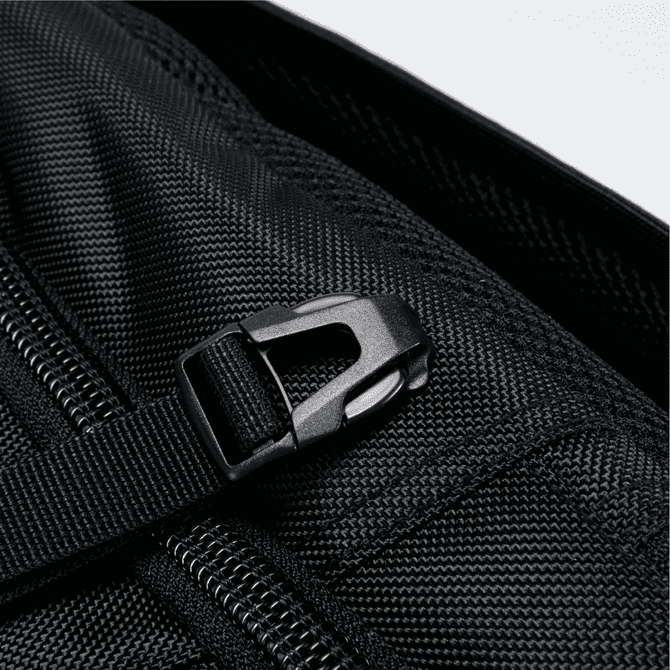 A close-up of a black Eiger Backpack showcasing a zipper and strap detail. It has a logo on the fabric.