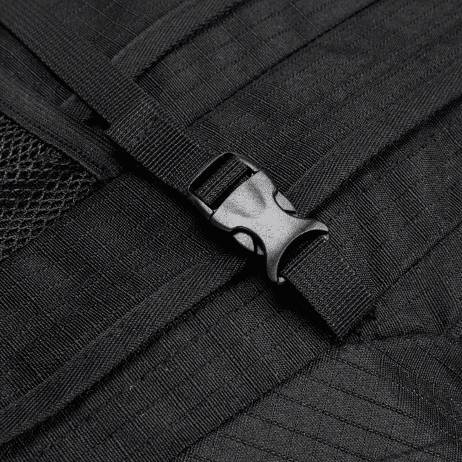A close-up of a black backpack strap featuring a plastic buckle and textured fabric.