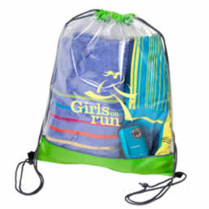 A clear PVC drawstring bag with a green base, containing towels and a portable device. It features a logo.