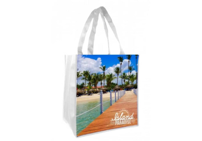 A tote bag featuring a vibrant tropical scene with palm trees and a wooden walkway, displayed against a white background.