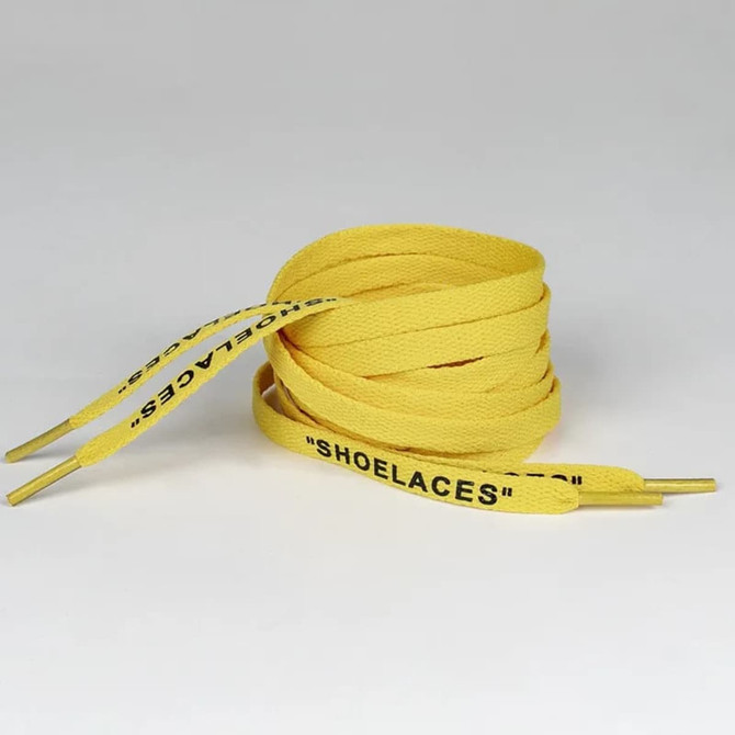 A pair of yellow shoelaces with black text on the ends, coiled neatly on a neutral background.
