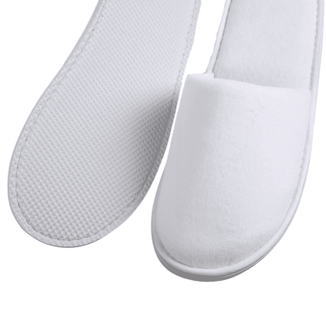 A pair of white hotel slippers with textured and smooth surfaces, featuring a simple design and soft materials.