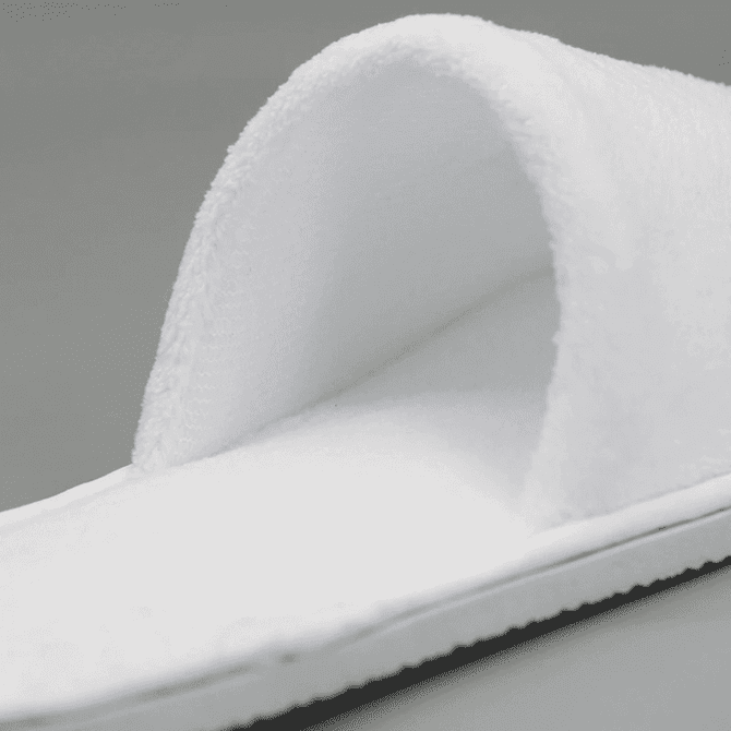 Open toe hotel slippers in white, featuring a soft, plush design and a textured sole.
