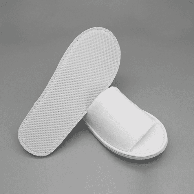 Open toe hotel slippers in white, featuring a textured sole and a simple design.
