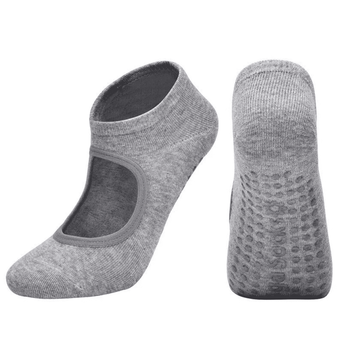 A pair of grey yoga socks with an open top and textured grip on the sole, featuring a logo.