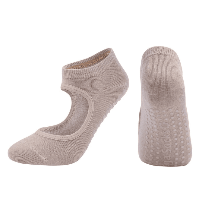 A pair of beige yoga socks with an open top and grip dots on the sole. The product features a logo.