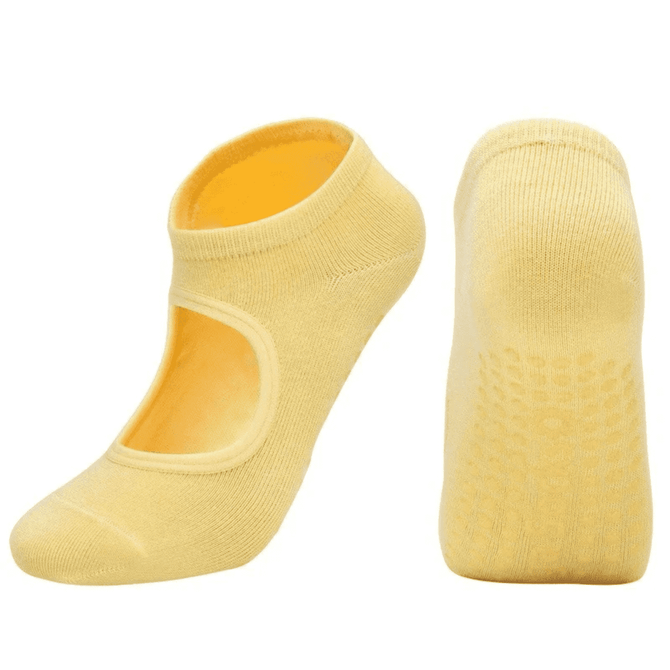 A pair of yellow open-top yoga socks with a non-slip grip on the soles. The socks have a logo on them.