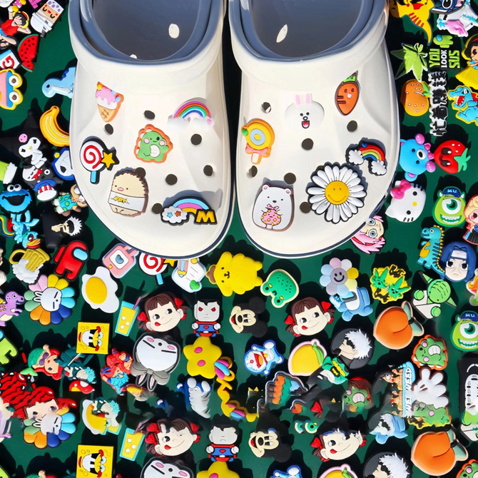 A pair of white shoes adorned with colourful PVC shoe charms, surrounded by a vibrant assortment of various designs.