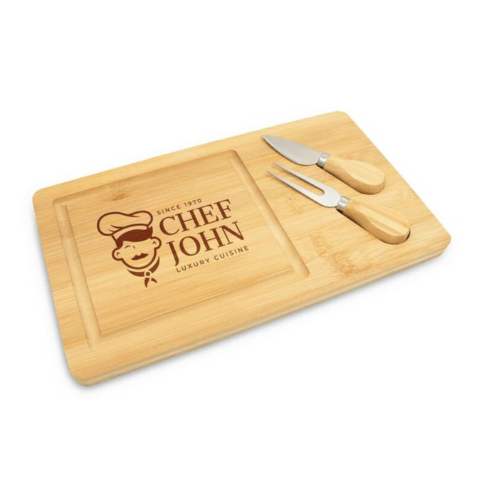 A bamboo cheese board with two metal knives, featuring a logo and a carved area for serving.